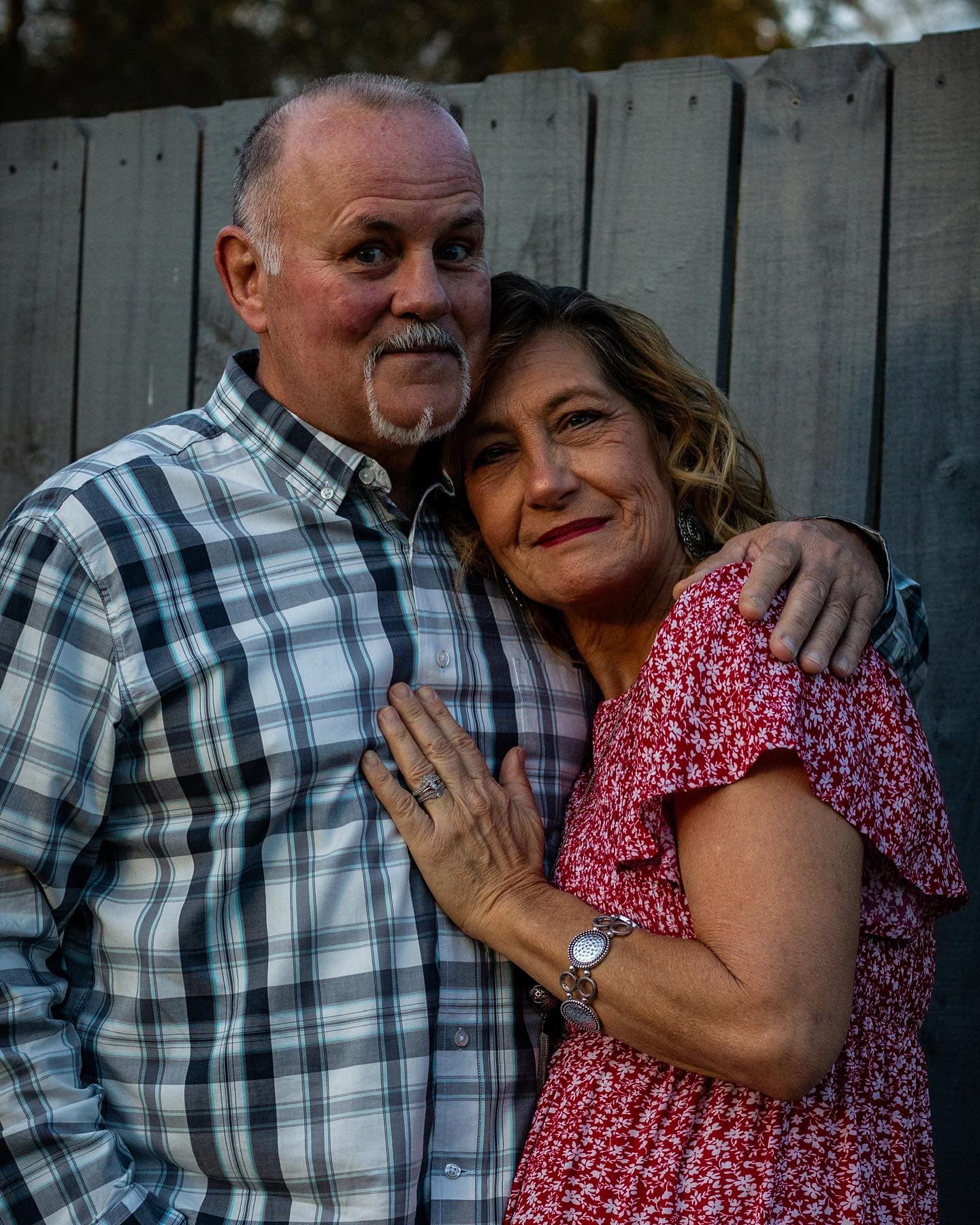 A couple standing close together in tall grass at golden hour