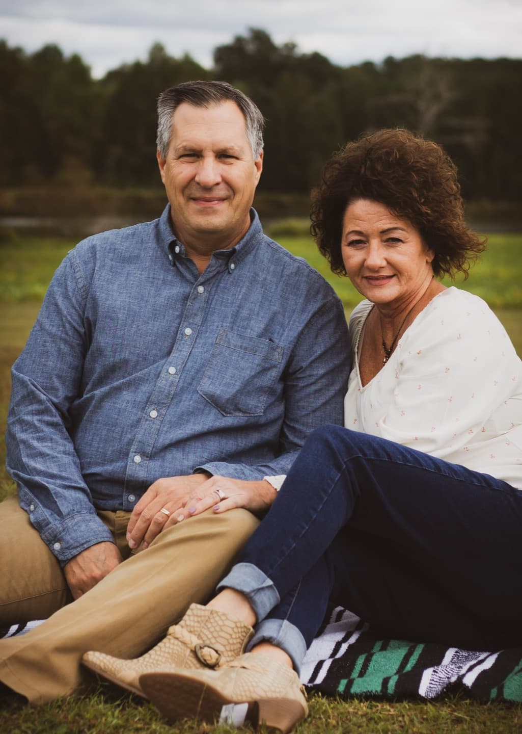 A couple seated together on the grass in soft evening light
