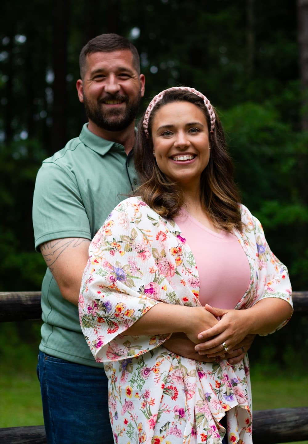 A couple smiling together against a wooden fence