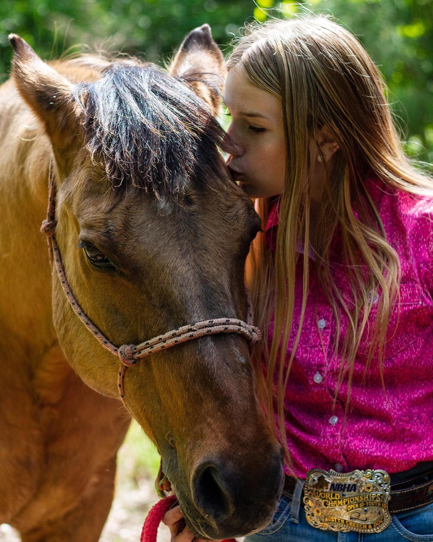 A girl resting her head against her horse's neck