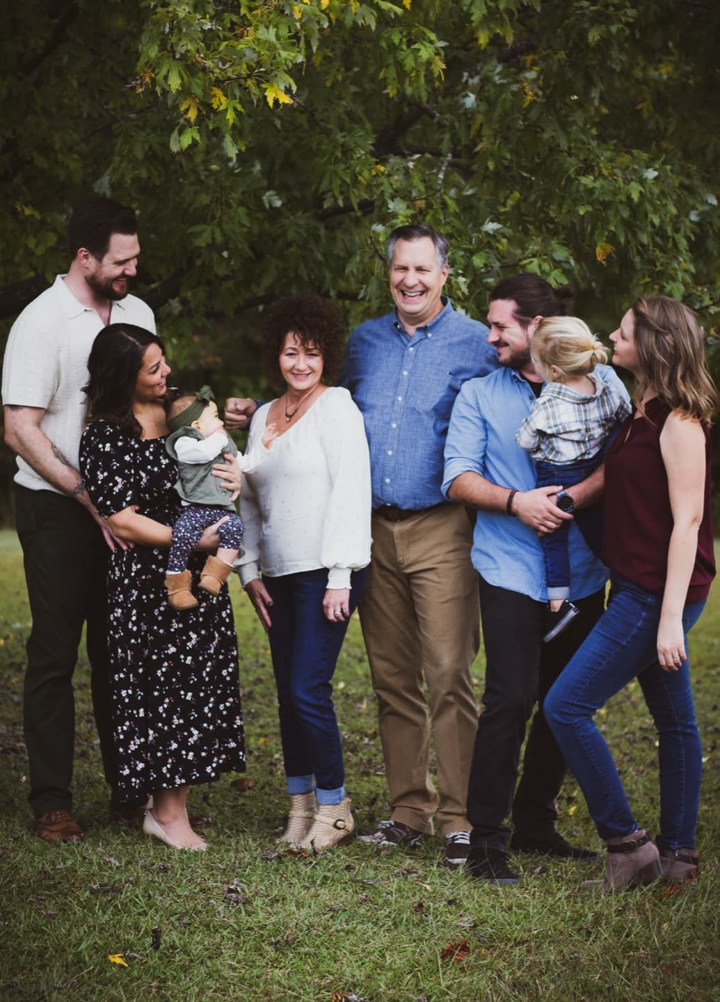A multi-generation family laughing together under the trees