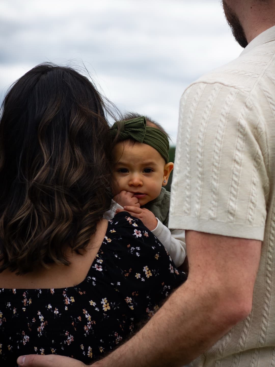 A baby peeking over her mother's shoulder