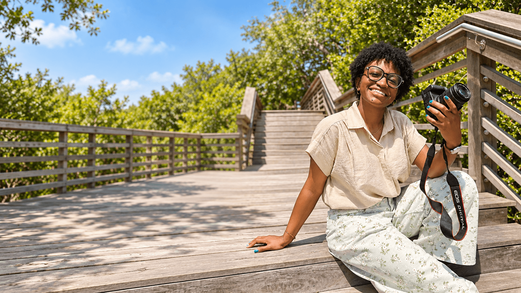 Telondra Reynolds sitting on a boardwalk holding her camera, smiling at the camera
