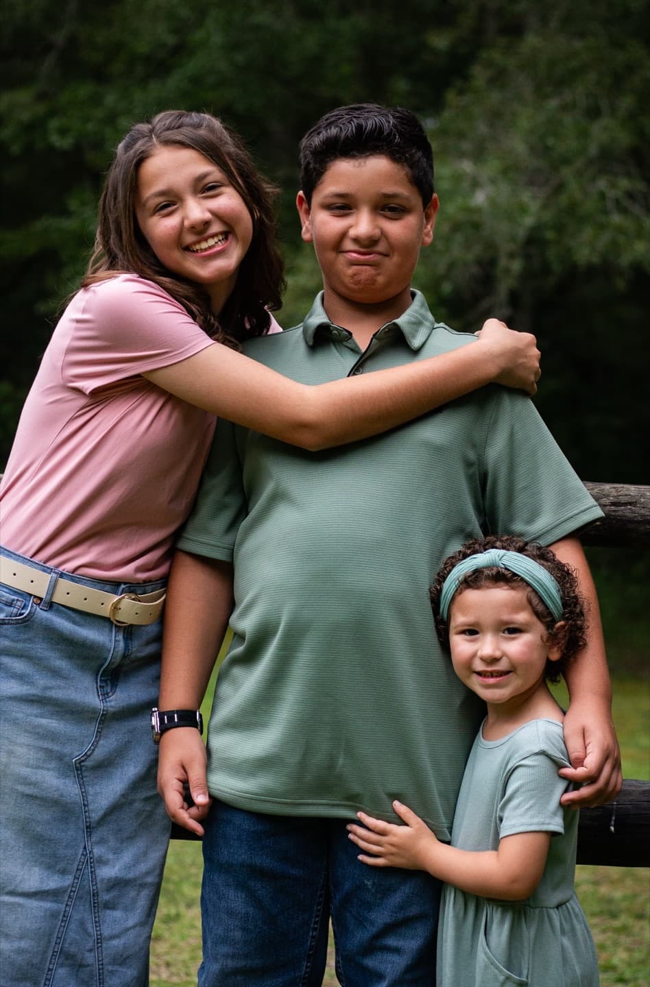 Three siblings hugging outdoors