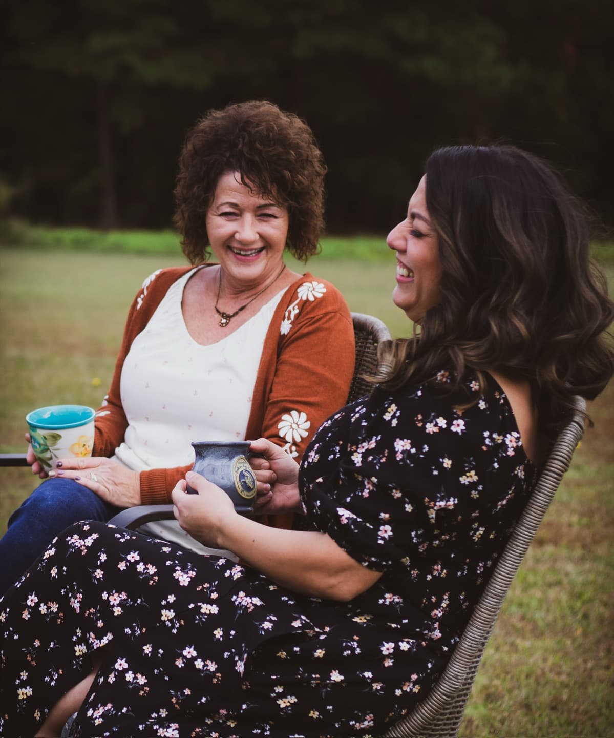 Two women laughing together over mugs in the afternoon