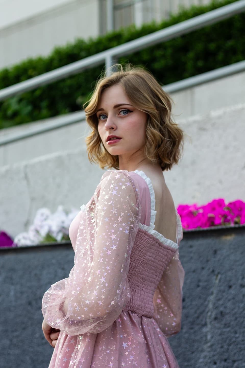 A young woman in a pink star-print dress turned toward the camera
